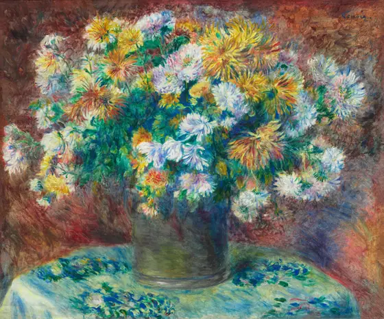 Orange, yellow, and white flowers in a brown vase on a round table, with a blue-green floral tablecloth and mottled, brownish background.