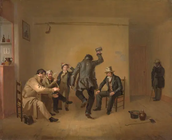 In a beige room, a group of light-skinned men of various ages and a young boy clap as a figure in tattered clothing at center, his back to the viewer, dances and holds a tin cup in the air.