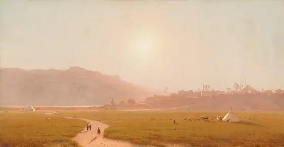 A dirt path winds through a field of gold-green grass back to a town built on low hills in this horizontal, densely hazy landscape painting. Several minuscule people walk on the path and at least one person rides a horse.