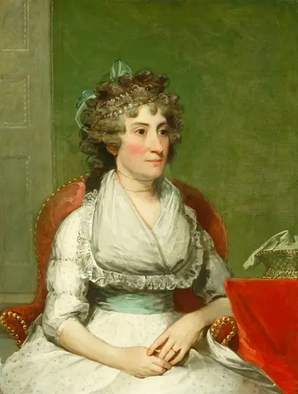 This is a painting of a woman depicted from the waist up. She is seated in a red armchair with gold details, slightly turned to the right, with her hands resting in her lap.
