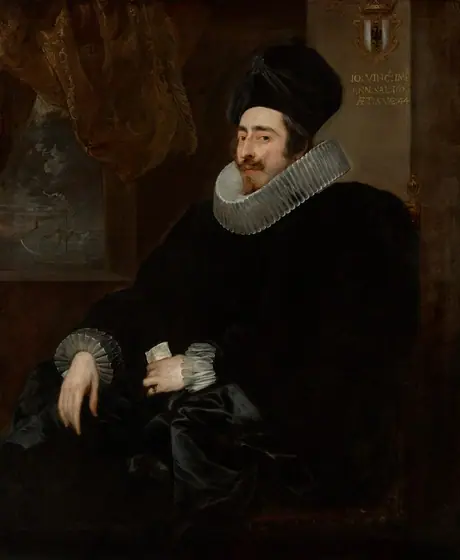 Shown from the knees up, a pale-skinned man wears a tall, black hat, wide white ruffs at the neck and cuffs, and a voluminous black garment in this vertical portrait painting.