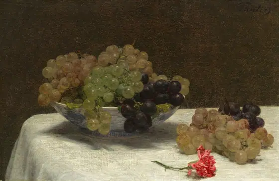 A blue and white bowl overflowing with grapes, two loose bunches of grapes, and a vivid pink carnation lie on a white tablecloth against a dark brown background in this still life painting.