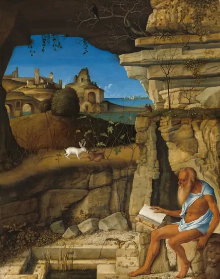 A bearded and balding man with deeply tanned skin, dressed only in a strip of robin’s egg-blue fabric around his shoulders and hips, sits reading a book on a rock at the entrance to a craggy cave, in front of a landscape in this vertical…