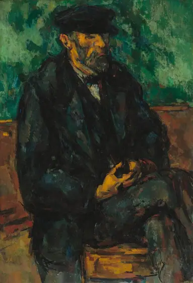 A bearded man with a coppery-peach completion, wearing a dark, navy-blue brimmed cap, vest, jacket, and pants sits on a wooden bench or chair against a green background in this vertical portrait.