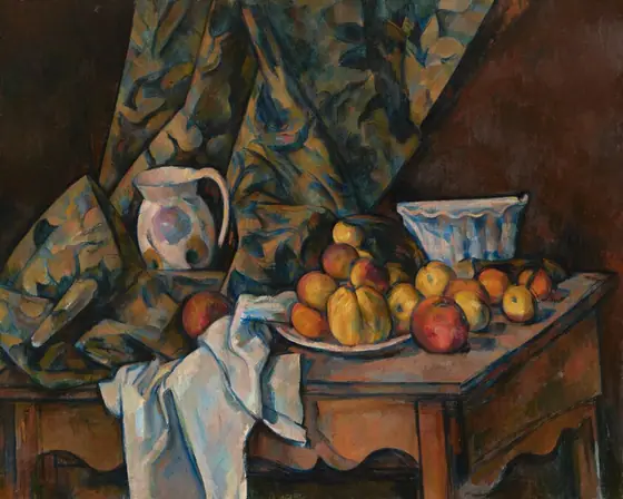 About a dozen rust-orange and golden yellow apples and peaches are arranged on a white plate next to white and floral-patterned cloths nestled around a white pitcher and bowl, all on a wood tabletop that tilts toward us in this nearly…