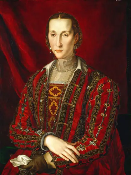 Shown from the hips up, a pale-skinned woman with a long, narrow face wears a richly decorated crimson-red dress in this vertical portrait painting. Her body angles to our left, and she looks in that direction with hooded brown eyes.