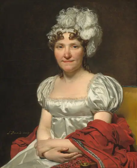 Shown from the lap up, a woman with peachy skin, wearing a white silk dress and feathered headpiece, sits facing and looking at us in a harvest-yellow, upholstered chair in this vertical portrait painting.