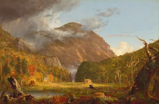 We look across a wide, low clearing at a mountain rising beyond rocky hills, which are mostly covered in pines and blazing red and orange autumn trees, in this horizontal landscape painting.