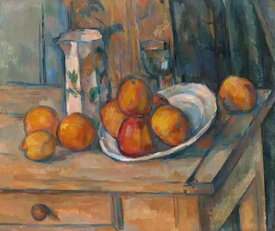 We look down onto nine pieces of fruit, a pitcher, a goblet, and a dish arranged on a rustic wood table in front of a floral curtain in this nearly square, loosely painted still life.