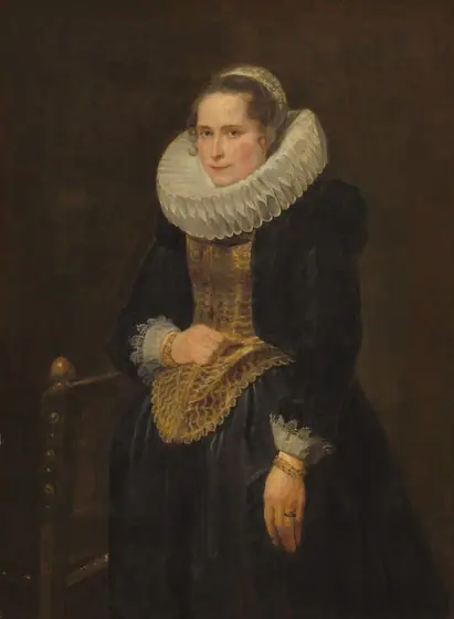 Shown from the knees up, a pale-skinned woman wears a wide, pleated collar and a black gown in this vertical portrait painting. Her body is angled to our left, and she looks at us from the corners of her light brown eyes.