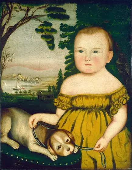 The image displays a child standing and facing forward. The child has a round face with rosy cheeks, wide blue eyes, and a small closed mouth. The child's hair is light and short.