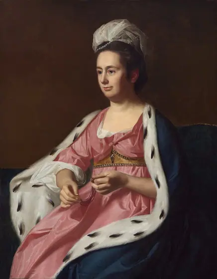 Shown from the knees up, a pale-skinned woman looking off to the left from her seat on a divan wears a carnation-pink gown and a fur-lined cloak in this vertical portrait painting.