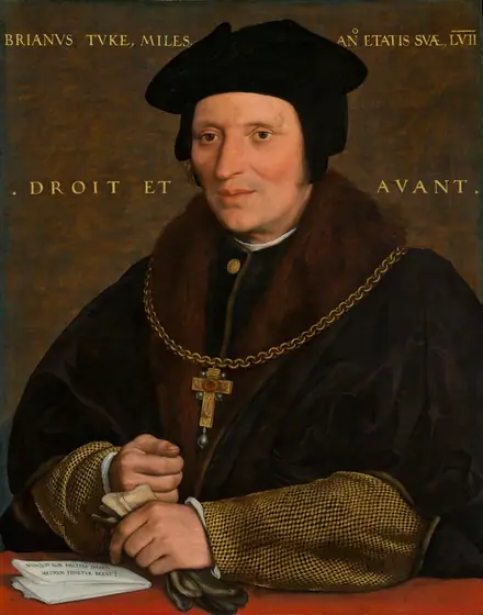 Shown from the waist up, a cleanshaven man with pale, peachy skin, wearing a black cap and a voluminous fur-lined, black cloak, is positioned behind a crimson-red ledge or tabletop in this vertical portrait painting.
