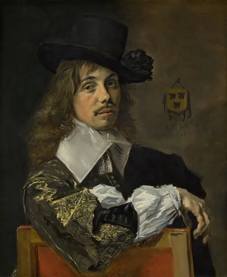 Shown from the waist up, a light-skinned man sits sideways in a wooden chair so the arm closer to us rests along the chair’s back in this vertical portrait painting. Brushstrokes are visible throughout, especially in the clothing and hair.