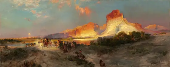 Sheer, vertical, cliffs, brightly lit in cream white and rust orange by the low sun, tower over a band of people riding horses into the distance in this long, horizontal landscape painting.