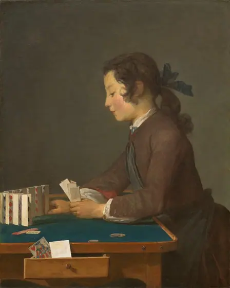 Shown from about the lap up, a young person with brown hair and a peachy complexion faces our left in profile as he leans onto a table and sets folded playing cards up in a row in this vertical painting.