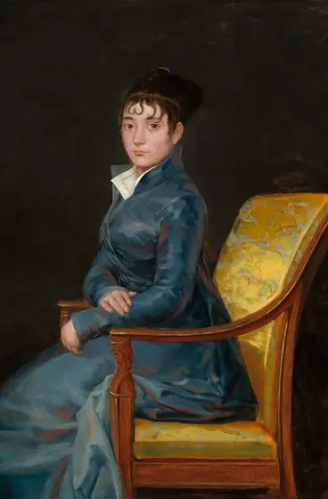 Shown from the knees up, a pale-skinned woman wearing a muted, sapphire-blue gown sits ramrod straight in a chair and looks at us in this vertical portrait painting.